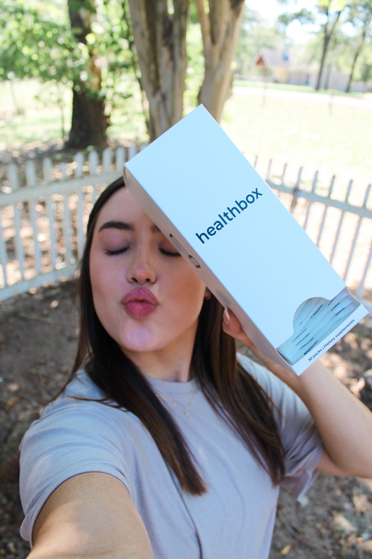 Person holding a Healthbox box outdoors with trees in the background