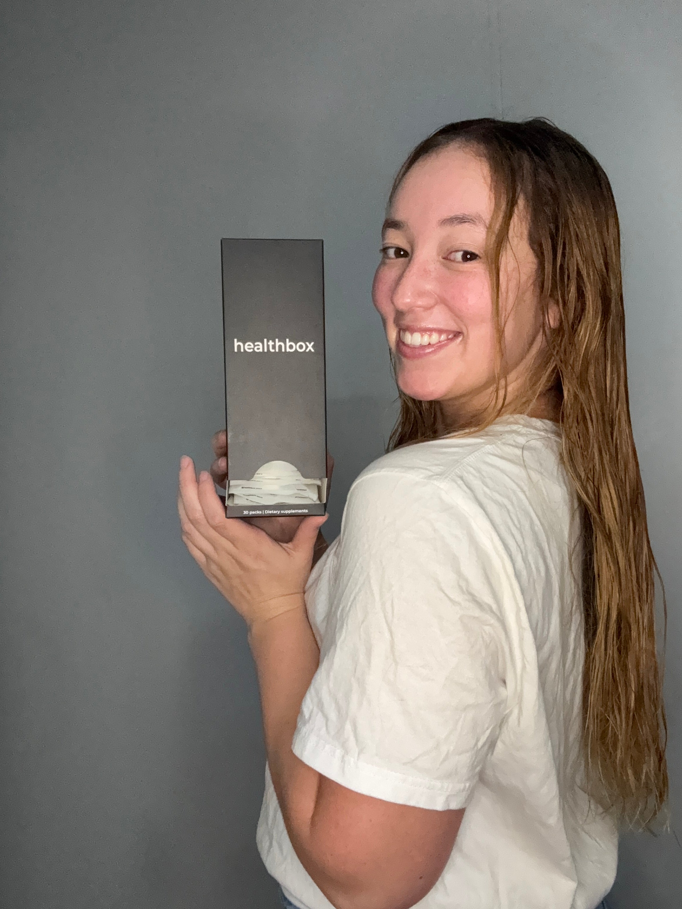 Person holding a Healthbox product box against a gray background