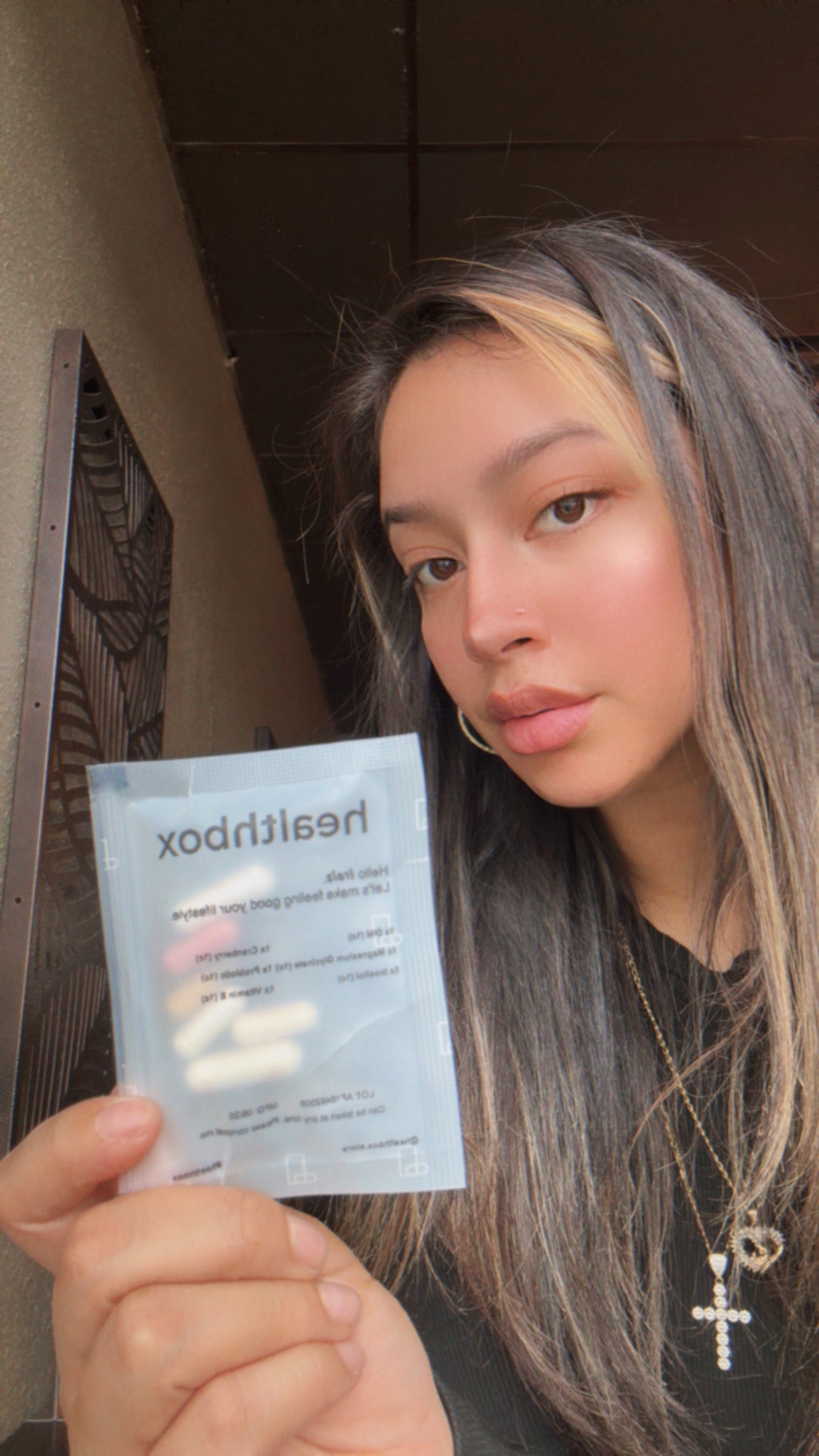 Person holding a Healthbox packet with text and images, standing outdoors.