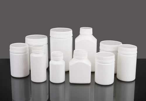 Collection of white plastic containers on a reflective surface with a dark background