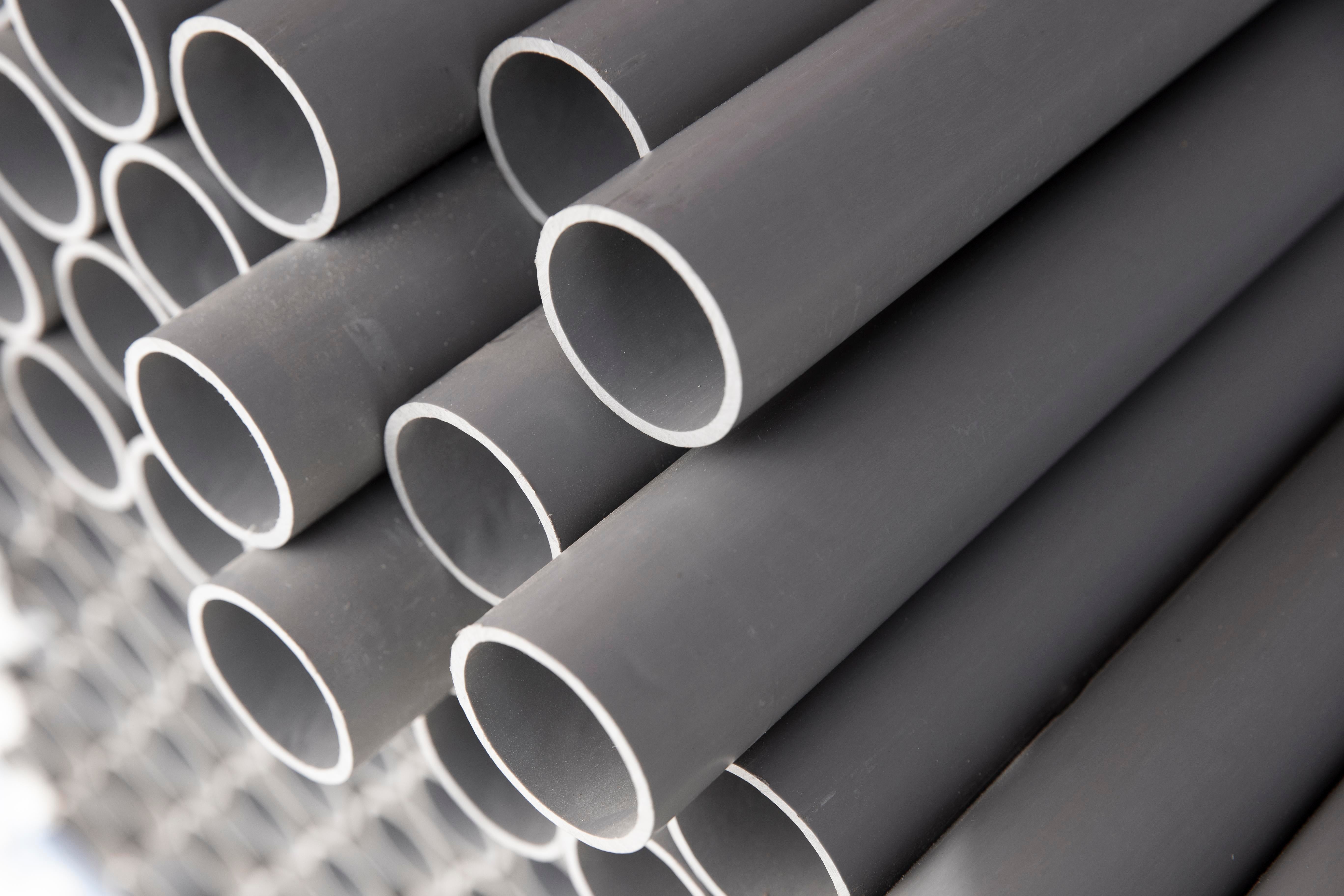 Stack of gray PVC pipes on a grid background